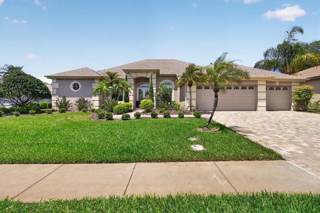 A single-story house with a beige exterior, a three-car garage, and a paved driveway — 4052 CAPITOL DRIVE, PALM HARBOR, FL