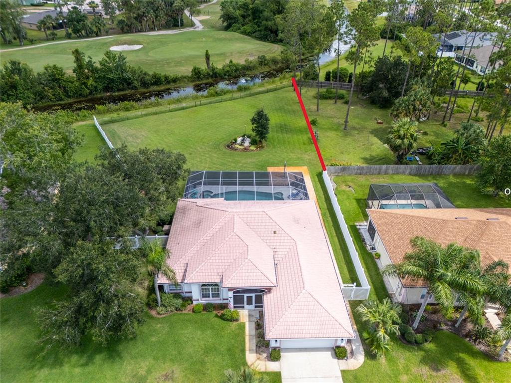 An aerial view shows a house with a pool cage, large backyard, and adjacent golf course — 87 EASTWOOD DRIVE, PALM COAST, FL