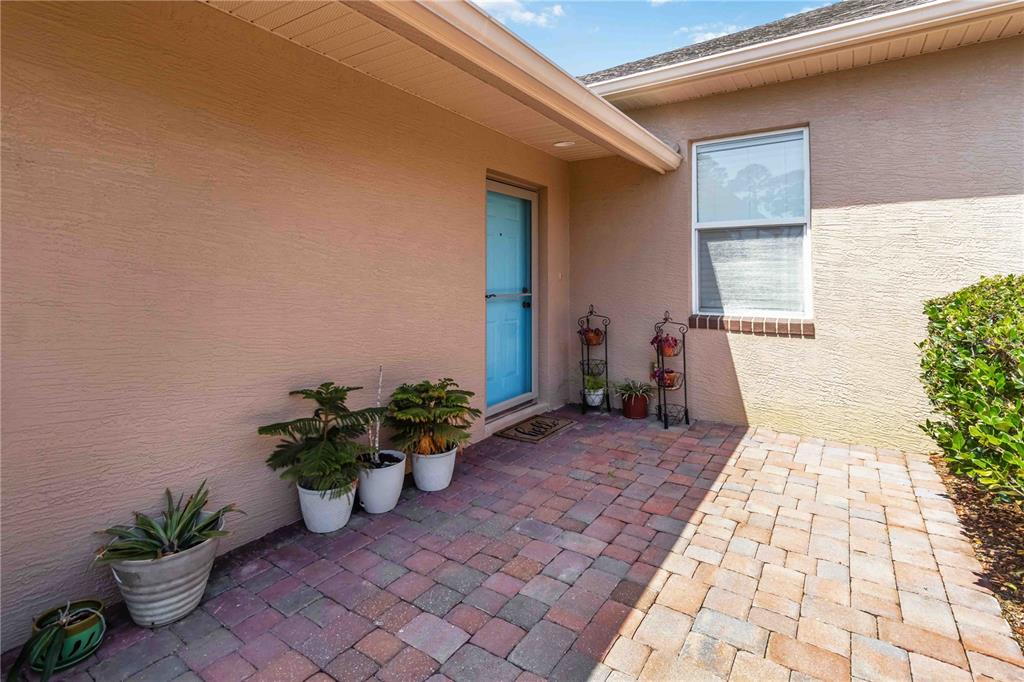 A paved patio leads to a blue front door on the side of a house — 112 TUSCANY VILLAS DRIVE UNIT 112, EDGEWATER, FL