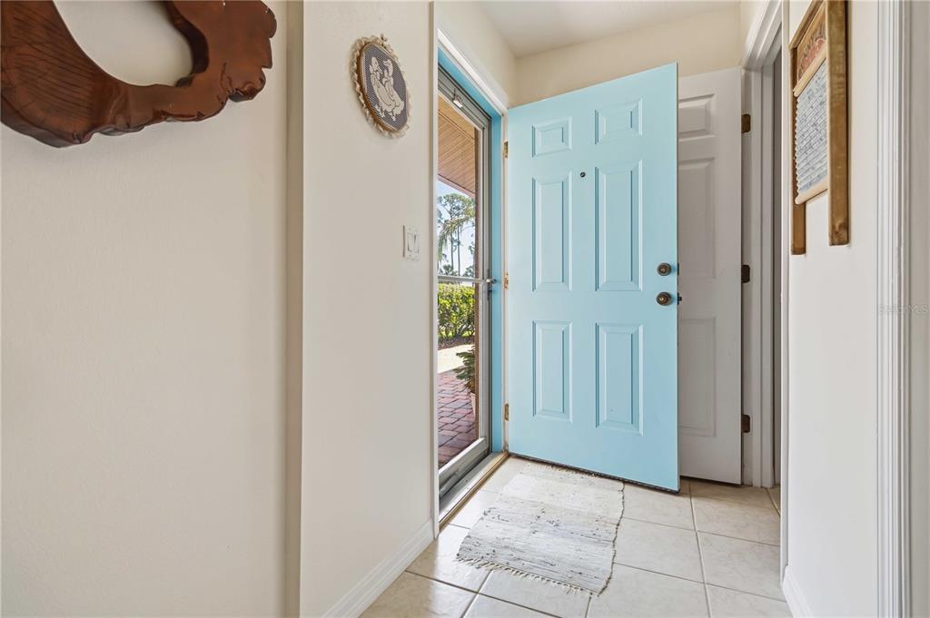 An entryway features a light blue front door, tiled flooring, and a screen storm door — 112 TUSCANY VILLAS DRIVE UNIT 112, EDGEWATER, FL