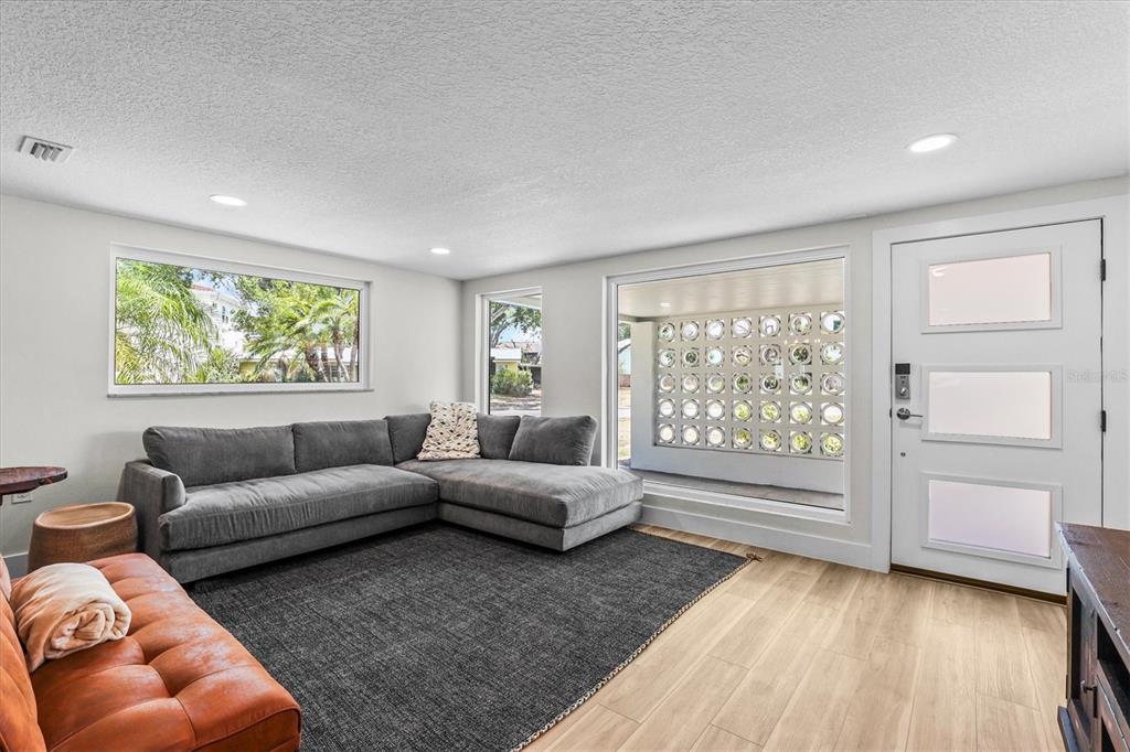 A living room features a gray sectional, a dark rug, and a decorative breeze block wall — 628 ONTARIO AVENUE, TAMPA, FL