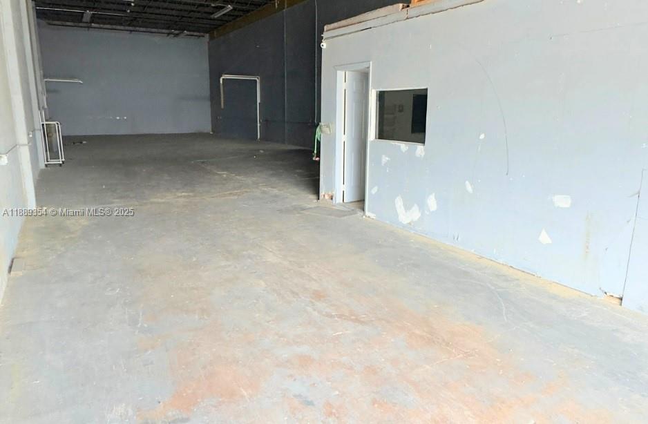 An empty industrial warehouse space features gray concrete walls and a small office enclosure — 4201 NW 37th Ct # B, Hialeah FL 33142, HIALEAH, FL