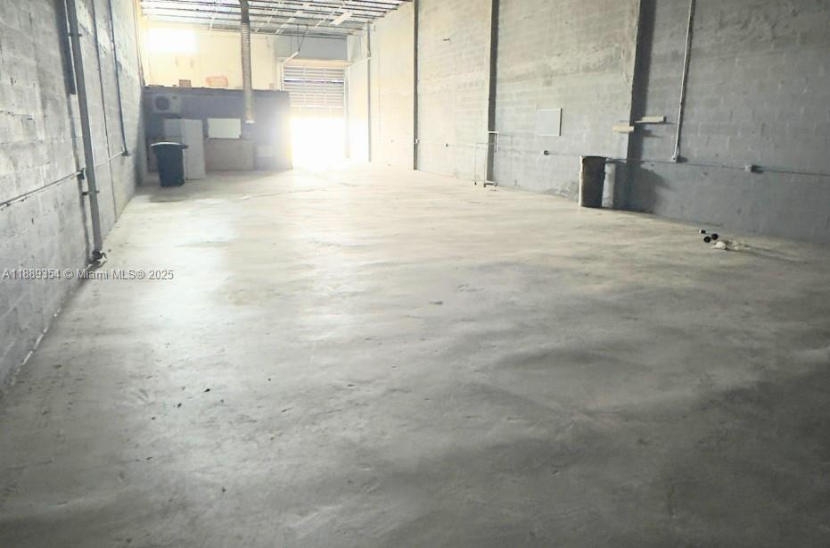 An empty industrial warehouse space features concrete walls, a concrete floor, and a roll-up door — 4201 NW 37th Ct # B, Hialeah FL 33142, HIALEAH, FL