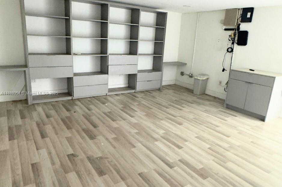 A room with light wood-look flooring, built-in gray shelving units, and a small cabinet — 4201 NW 37th Ct # B, Hialeah FL 33142, HIALEAH, FL