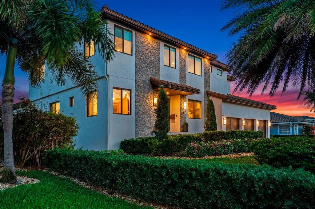 A two-story house with a stone facade, tile roof, and palm trees at dusk — 2060 ILLINOIS AVENUE NE, ST PETERSBURG, FL