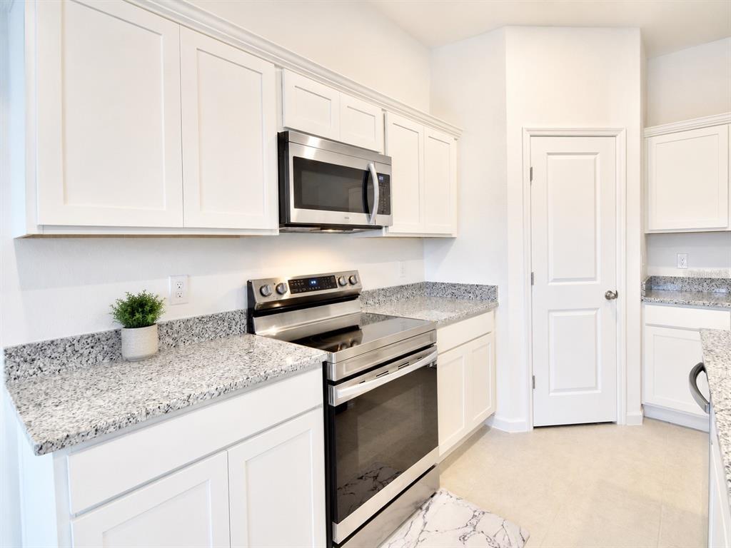 A kitchen features white cabinets, granite countertops, and stainless steel appliances — 2150 GOLD DUST DRIVE, CLERMONT, FL