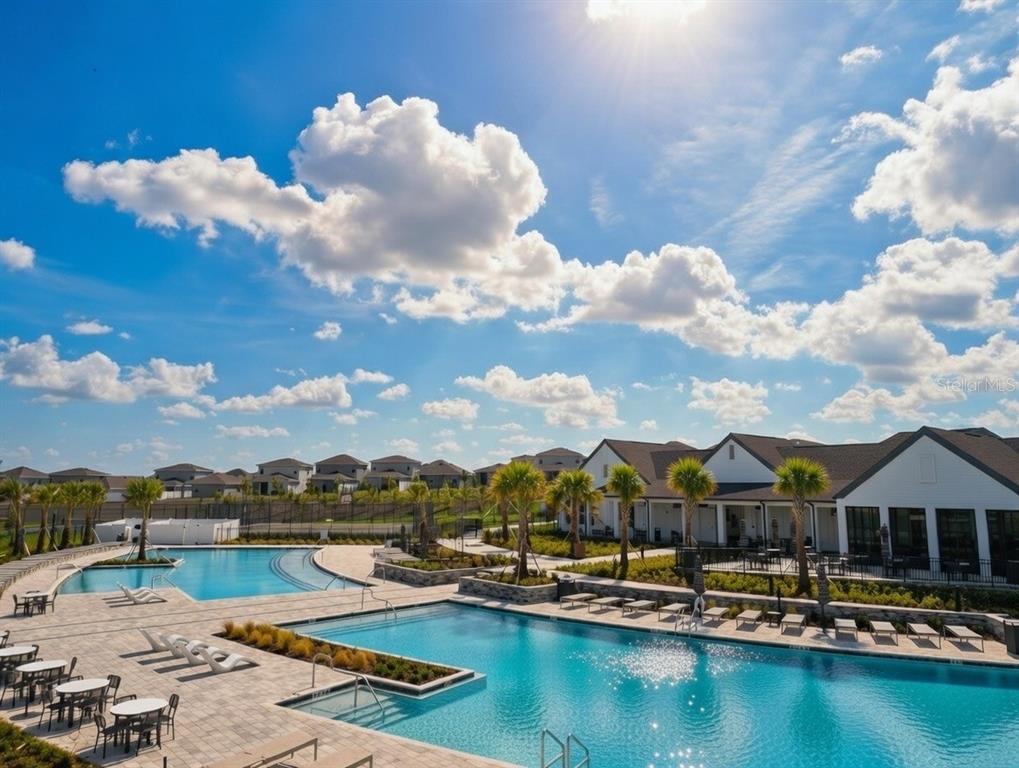 An outdoor swimming pool area with lounge chairs and a clubhouse under a sunny sky — 2150 GOLD DUST DRIVE, CLERMONT, FL