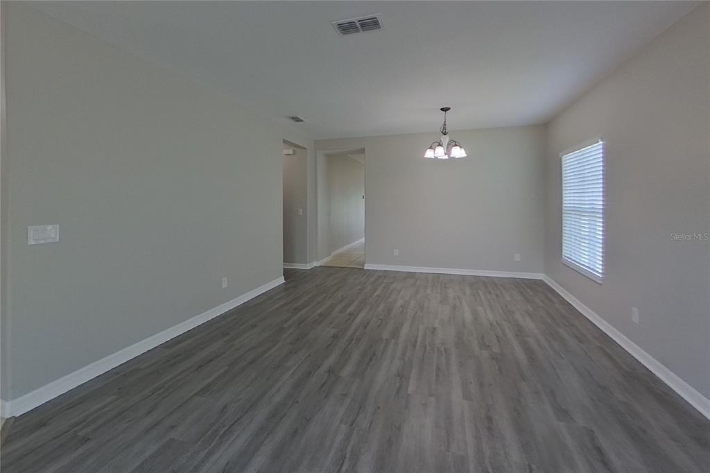 An empty room with gray wood-look flooring, light walls, and a hanging light fixture — 3720 BRIARWOOD ESTATES CIRCLE, ST CLOUD, FL