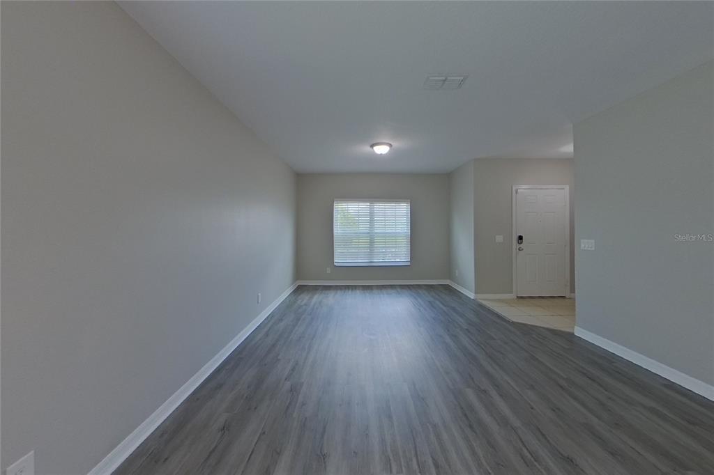 A living room with gray walls, wood-look flooring, a single window, and a white door — 3720 BRIARWOOD ESTATES CIRCLE, ST CLOUD, FL