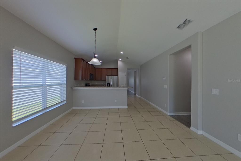 A tiled dining area opens to a kitchen with wooden cabinets and a breakfast bar — 3720 BRIARWOOD ESTATES CIRCLE, ST CLOUD, FL