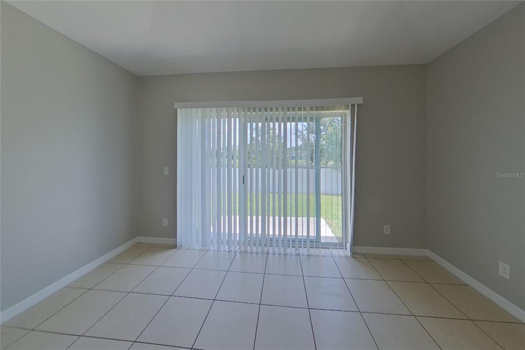 An empty room features light-colored tile flooring, gray walls, and a sliding glass door — 3720 BRIARWOOD ESTATES CIRCLE, ST CLOUD, FL