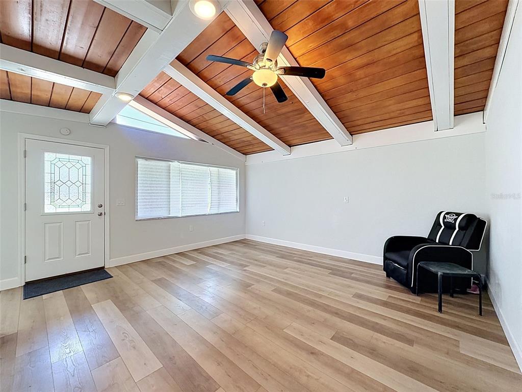 A living room features a vaulted wood-plank ceiling, exposed beams, and light-colored wood flooring — 14339 RICE ROAD, HUDSON, FL
