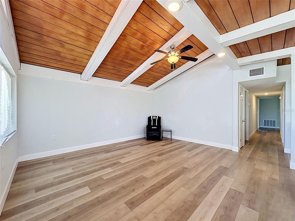 An empty room with wood-plank vaulted ceilings, light-colored walls, and wood-look flooring — 14339 RICE ROAD, HUDSON, FL