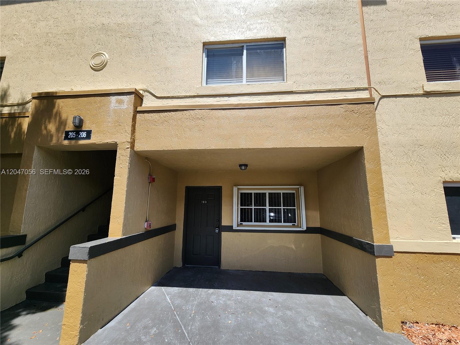 The exterior view shows a ground-level apartment entrance with a covered porch and stairs — 14901 SW 82nd Ter # 103, Miami FL 33193, MIAMI, FL