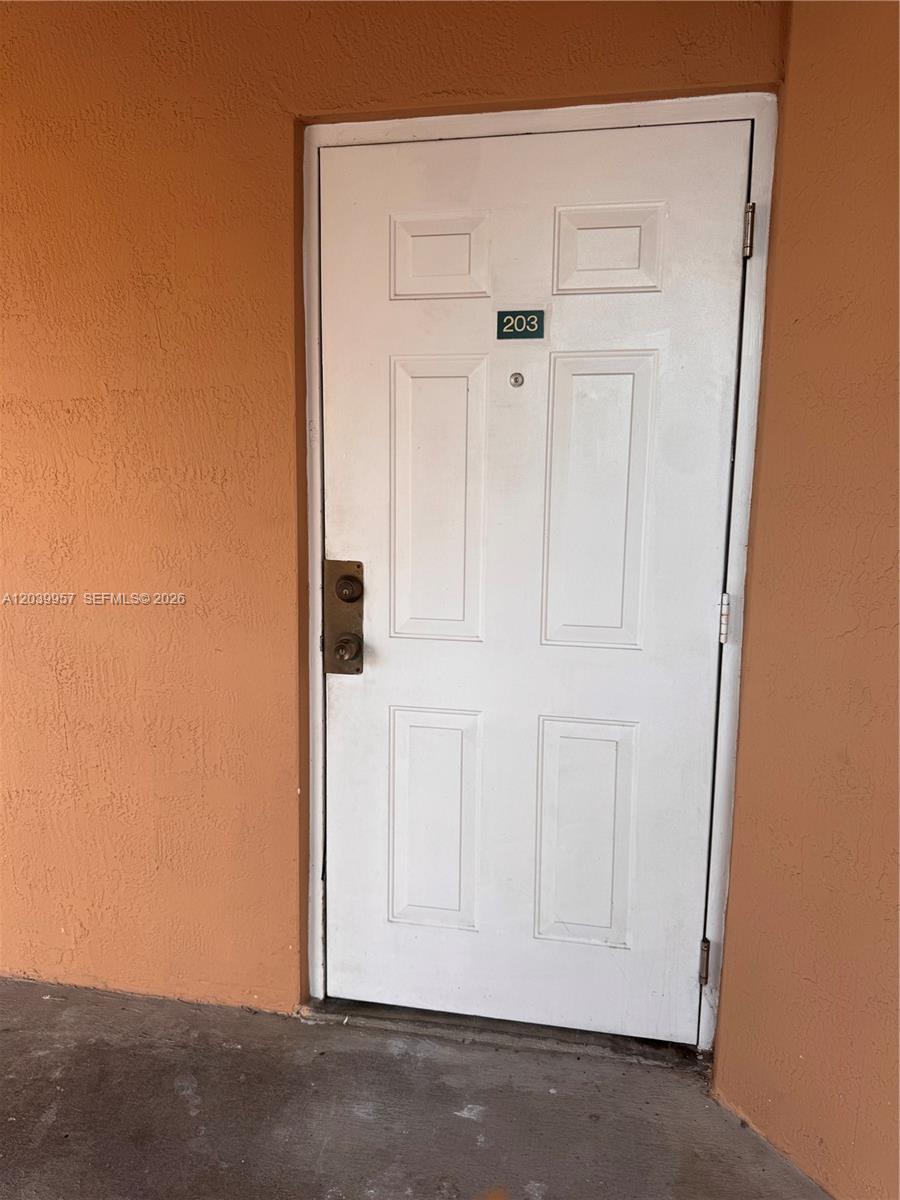 A white exterior door with the number 203 is set into an orange stucco wall — 7070 NW 177th St # 10, Hialeah FL 33015, HIALEAH, FL