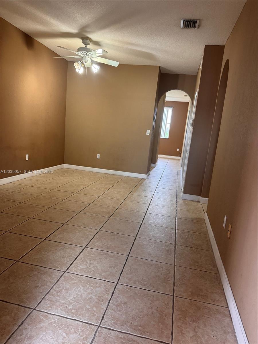 An empty room features tan walls, a ceiling fan, and light-colored square floor tiles — 7070 NW 177th St # 10, Hialeah FL 33015, HIALEAH, FL