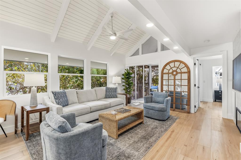 A bright living room features a vaulted ceiling, light wood floors, and blue armchairs — 5000 GASPARILLA ROAD UNIT VH20, BOCA GRANDE, FL