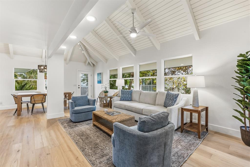 A bright living room features a vaulted ceiling, light wood floors, and blue upholstered furniture — 5000 GASPARILLA ROAD UNIT VH20, BOCA GRANDE, FL