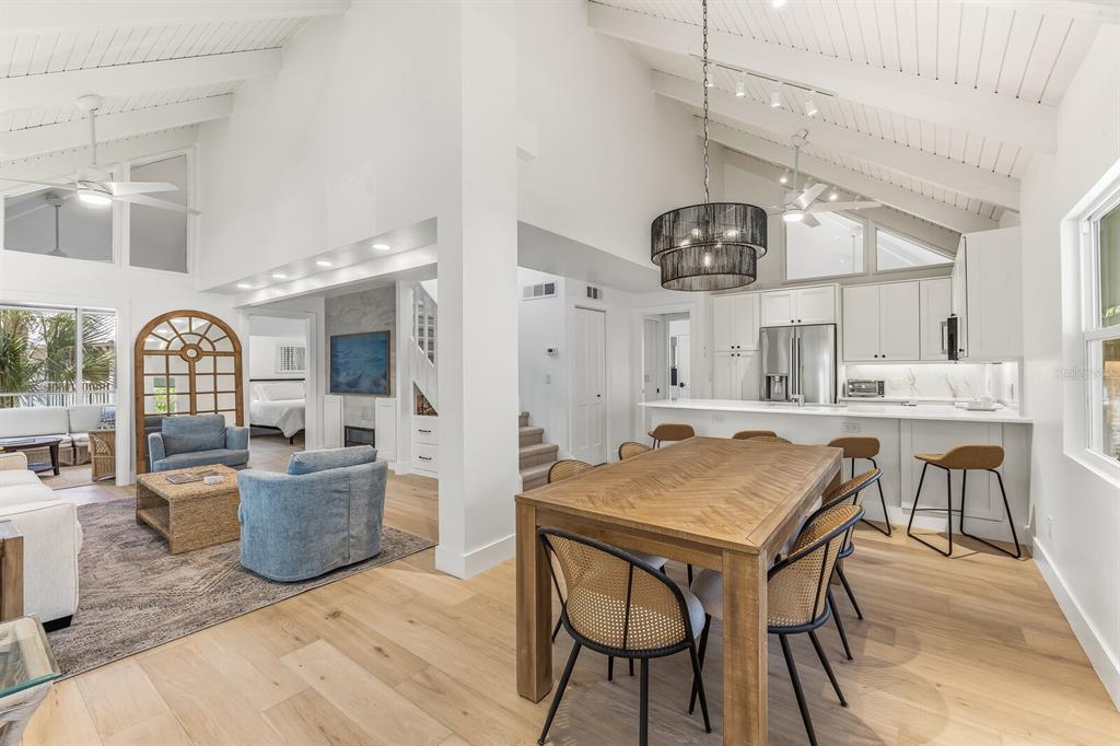An open-concept living and dining area features vaulted ceilings, light wood floors, and a modern kitchen — 5000 GASPARILLA ROAD UNIT VH20, BOCA GRANDE, FL