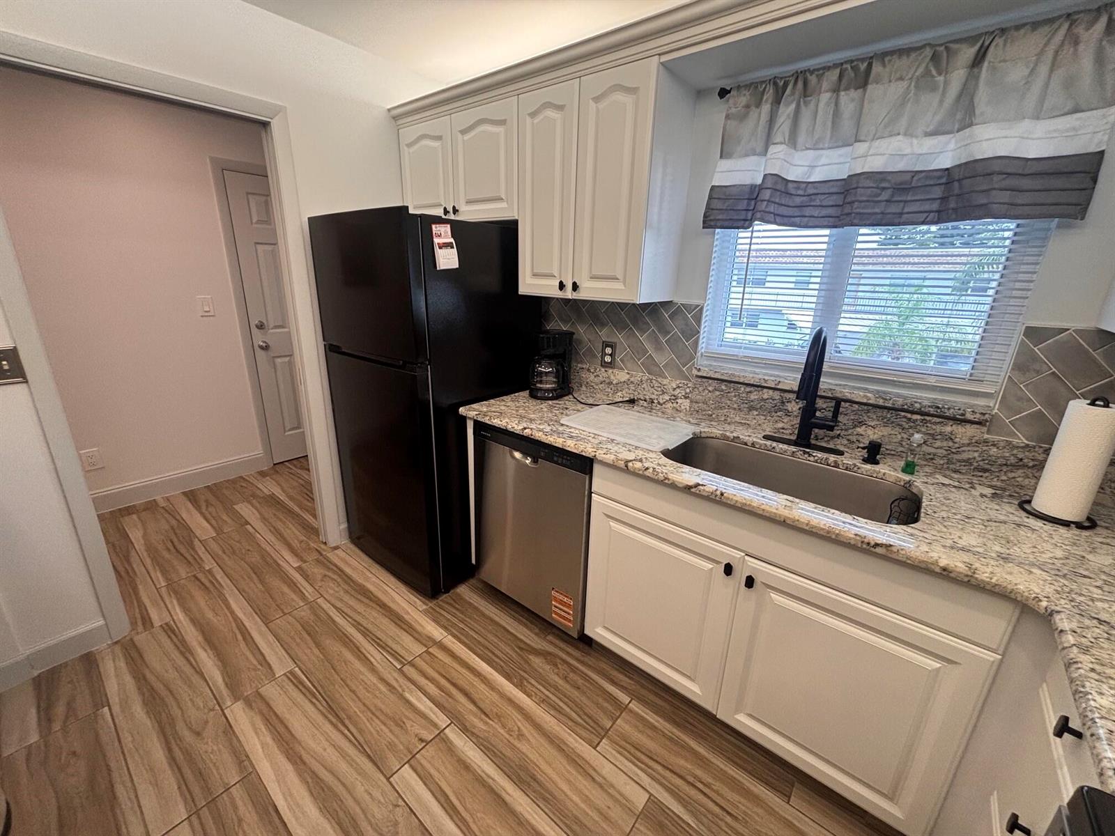 A kitchen features white cabinets, granite countertops, a stainless steel dishwasher, and a black refrigerator — 2950 SE Ocean Boulevard # 5, Stuart FL 34996, STUART, FL