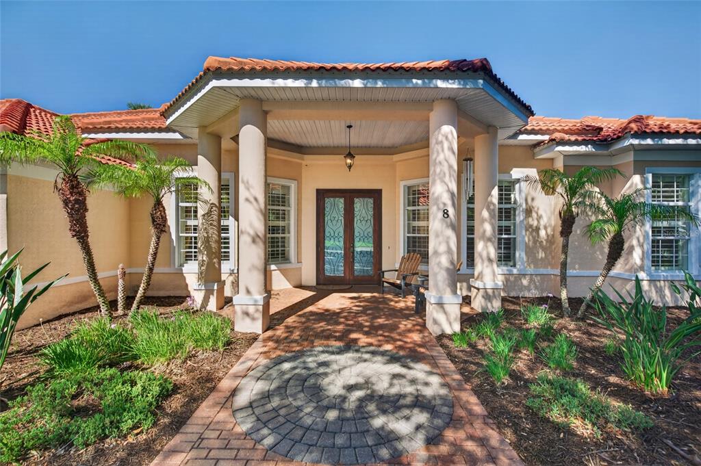 The front entrance of a house features a brick walkway, columns, and double glass doors — 8 OLD OAK DRIVE N, PALM COAST, FL
