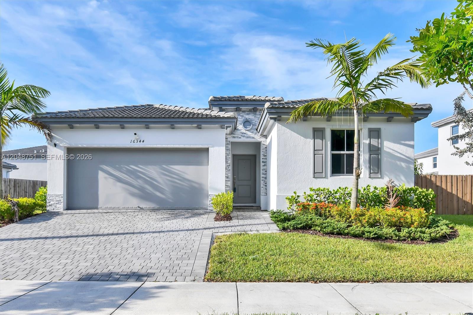 A single-story house with a white stucco exterior, a gray garage door, and a tiled roof — 16344 SW 290th St, Homestead FL 33033, HOMESTEAD, FL