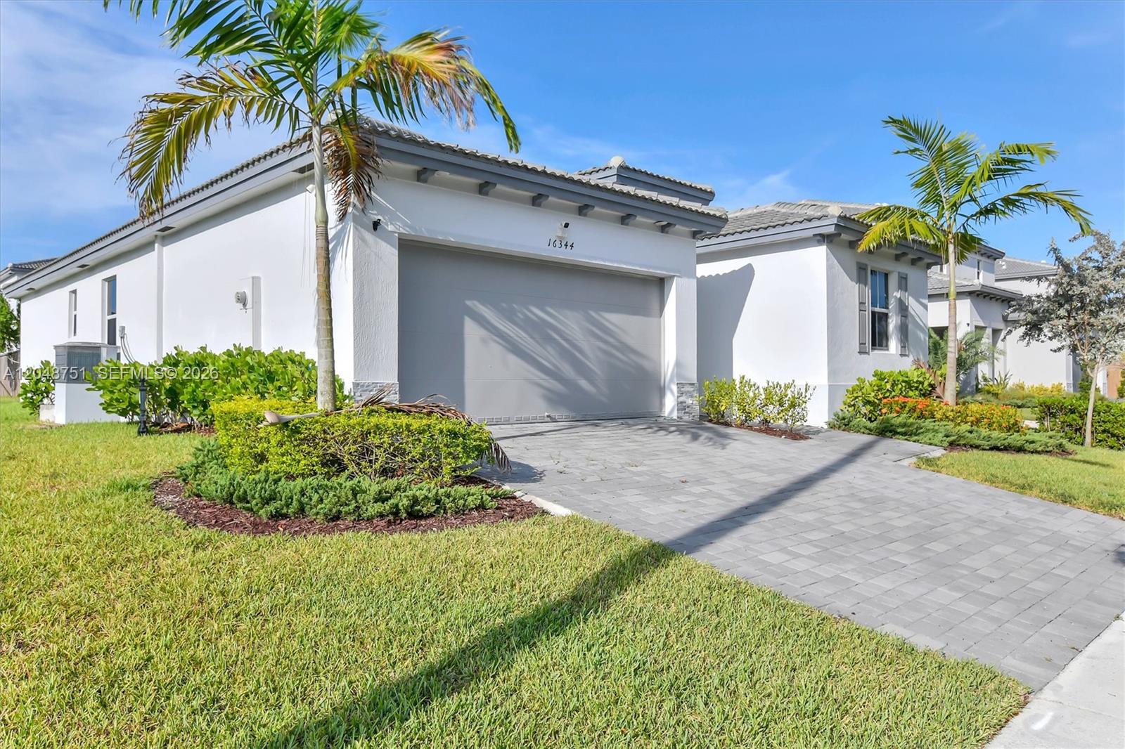 A white single-story house with a gray garage door and a paved driveway — 16344 SW 290th St, Homestead FL 33033, HOMESTEAD, FL