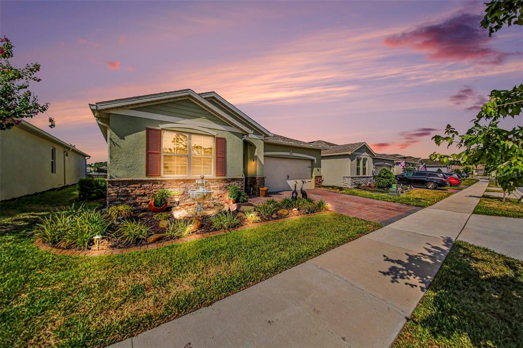 A single-story house with a stone facade, red shutters, and a front yard fountain — 17651 BLAZING STAR CIRCLE, CLERMONT, FL
