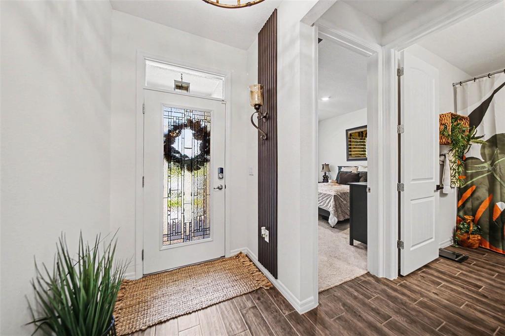 An entryway features a white front door, wood-look tile flooring, and a bedroom doorway — 17651 BLAZING STAR CIRCLE, CLERMONT, FL