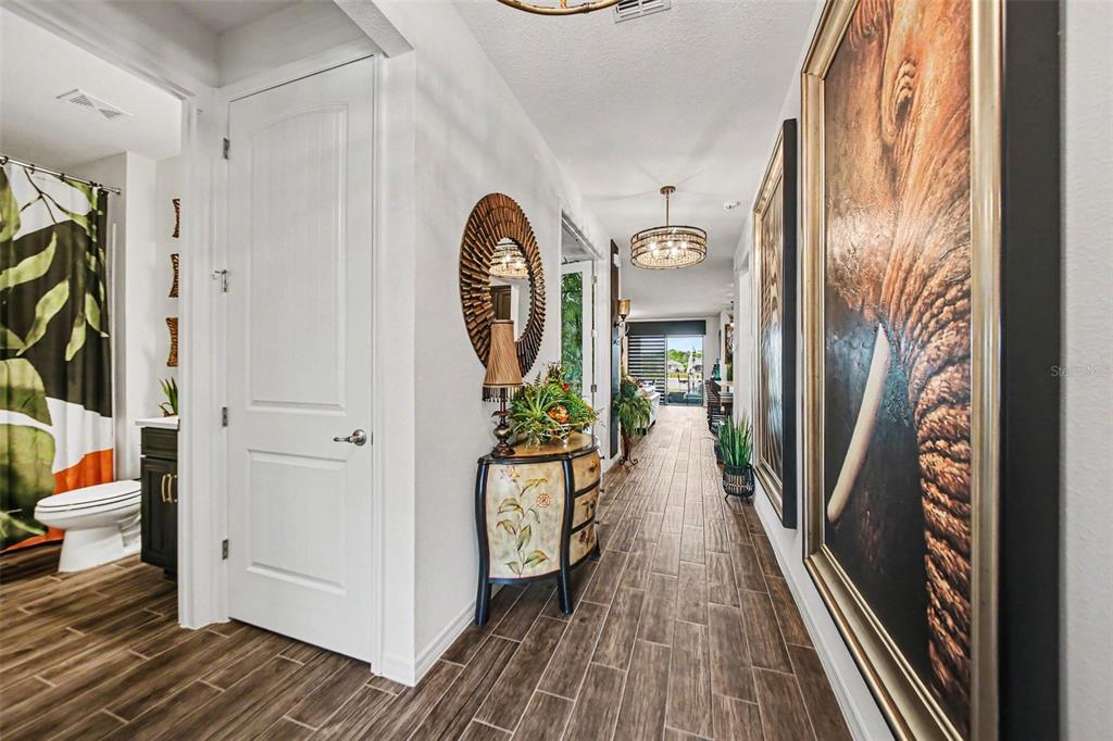 A hallway with wood-look tile flooring, an elephant painting, and a console table with mirror — 17651 BLAZING STAR CIRCLE, CLERMONT, FL