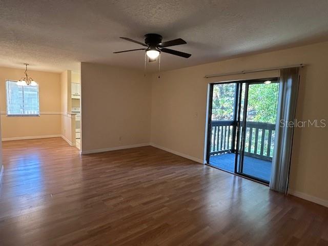 An empty living room with wood-look flooring, a ceiling fan, and a sliding glass door — 177 SPRINGWOOD CIRCLE UNIT C, LONGWOOD, FL