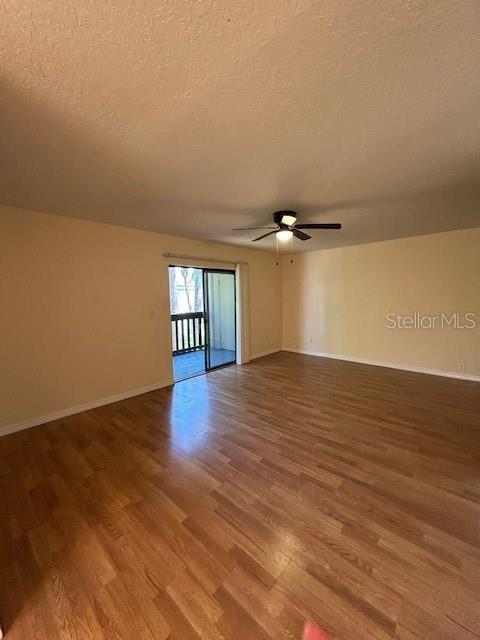 An empty living room features light-colored walls, wood-look flooring, a ceiling fan, and a balcony — 177 SPRINGWOOD CIRCLE UNIT C, LONGWOOD, FL