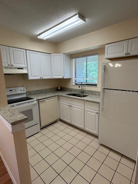 A kitchen features white cabinets, granite countertops, a white refrigerator, and a tiled floor — 177 SPRINGWOOD CIRCLE UNIT C, LONGWOOD, FL