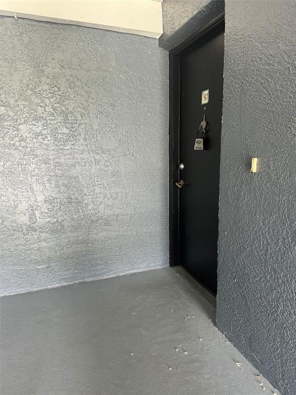 A black door with a lockbox is set into a gray textured wall on a porch — 4227 PERSHING POINTE PLACE UNIT 8, ORLANDO, FL