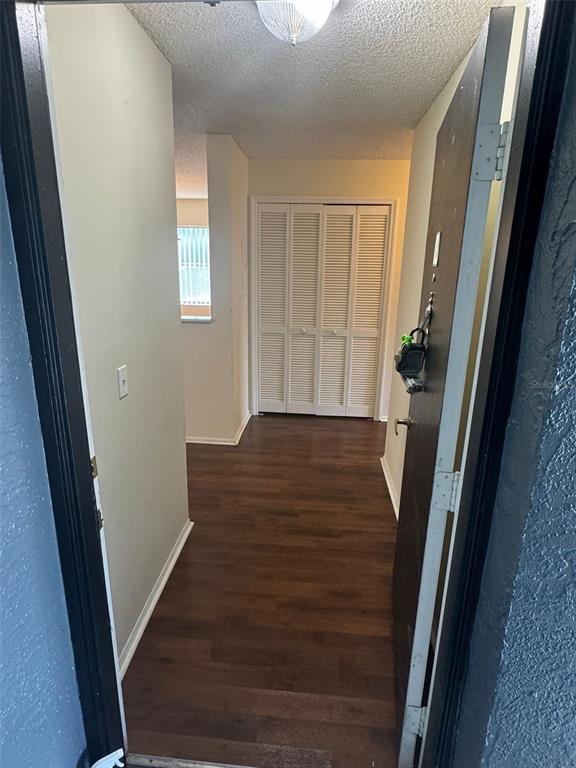 An entryway with dark wood-look flooring leads to a white louvered closet door — 4227 PERSHING POINTE PLACE UNIT 8, ORLANDO, FL