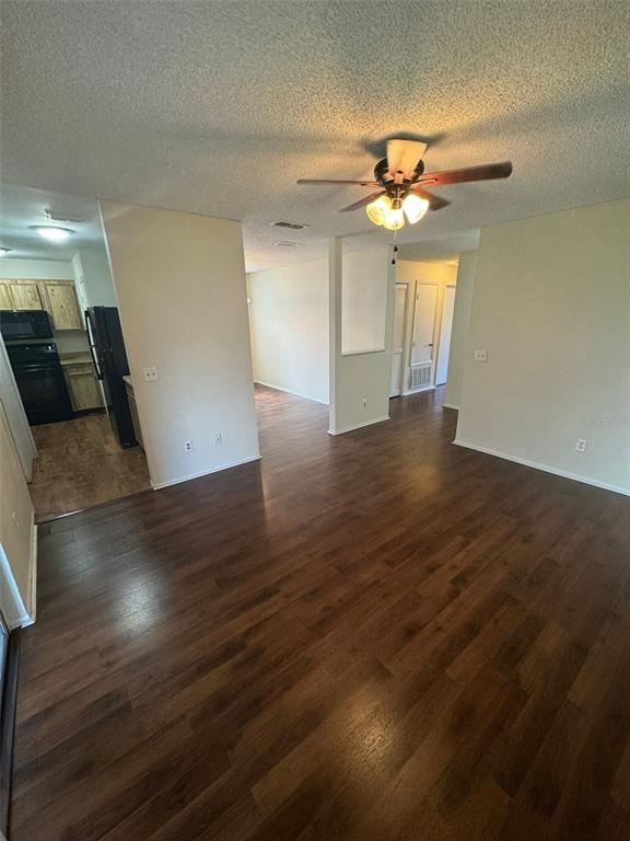 An open-concept living area with dark wood-look flooring, a ceiling fan, and an adjacent kitchen — 4227 PERSHING POINTE PLACE UNIT 8, ORLANDO, FL