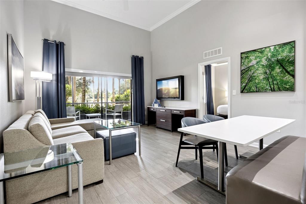 A living and dining area features a sofa, glass tables, a television, and large windows — 14501 GROVE RESORT AVENUE UNIT 1111, WINTER GARDEN, FL