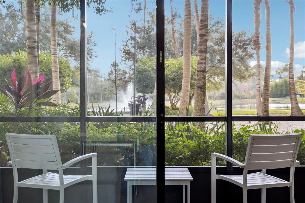 A view through a sliding glass door shows a screened patio with chairs and palm trees — 14501 GROVE RESORT AVENUE UNIT 1111, WINTER GARDEN, FL