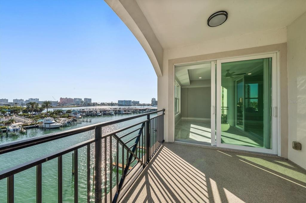 A balcony with a black metal railing overlooks a marina and a distant city skyline — 211 DOLPHIN POINT UNIT 401, CLEARWATER BEACH, FL