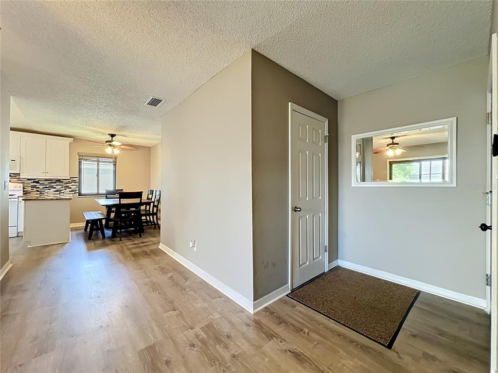 An interior view showing a dining area with wood-look flooring and an adjacent entryway — 116 SPRINGWOOD CIRCLE UNIT D, LONGWOOD, FL