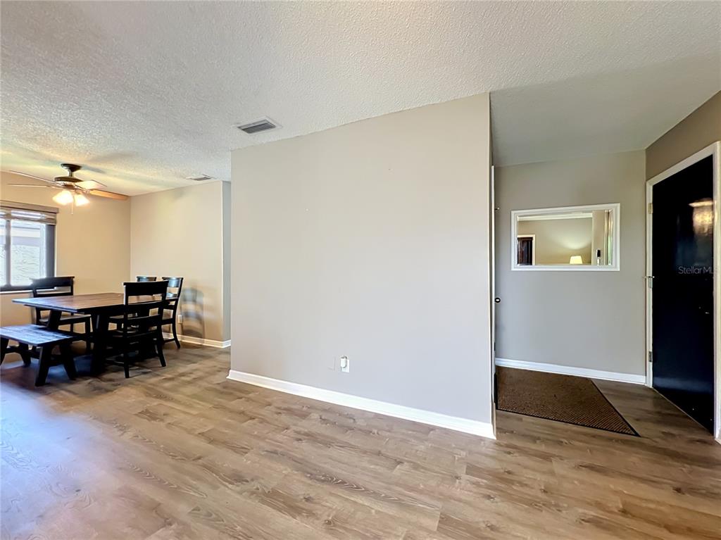 A dining area with a wooden table and chairs sits adjacent to an entryway hallway — 116 SPRINGWOOD CIRCLE UNIT D, LONGWOOD, FL