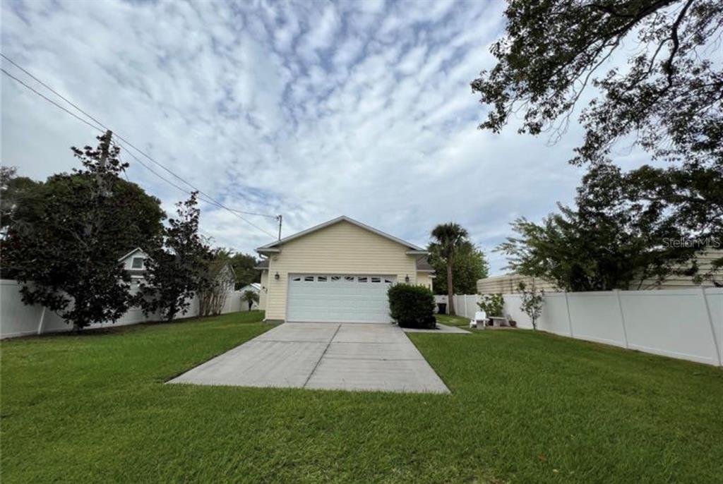 A detached garage with light yellow siding sits at the end of a concrete driveway — 1011 MINNESOTA AVENUE, ST CLOUD, FL