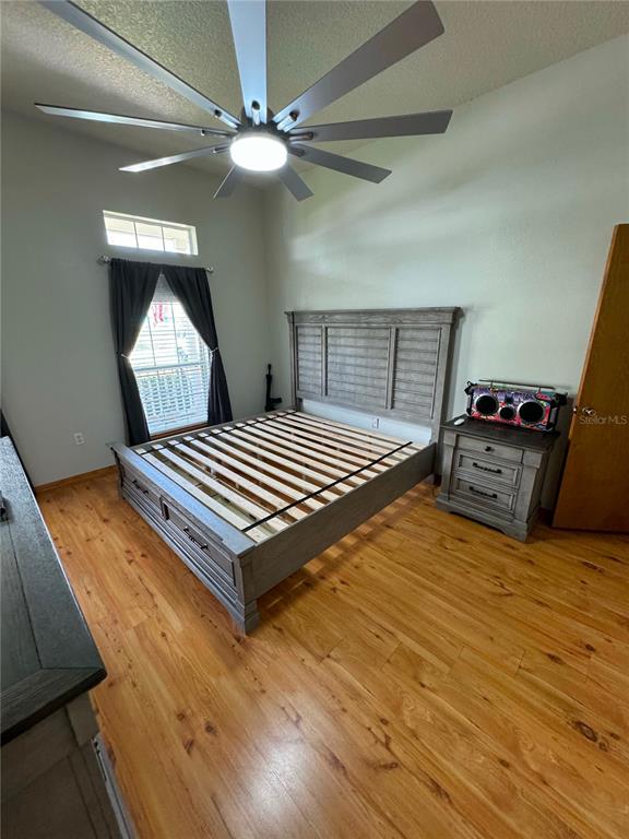 A bedroom features a wooden bed frame, a nightstand, a ceiling fan, and wood flooring — 1011 MINNESOTA AVENUE, ST CLOUD, FL