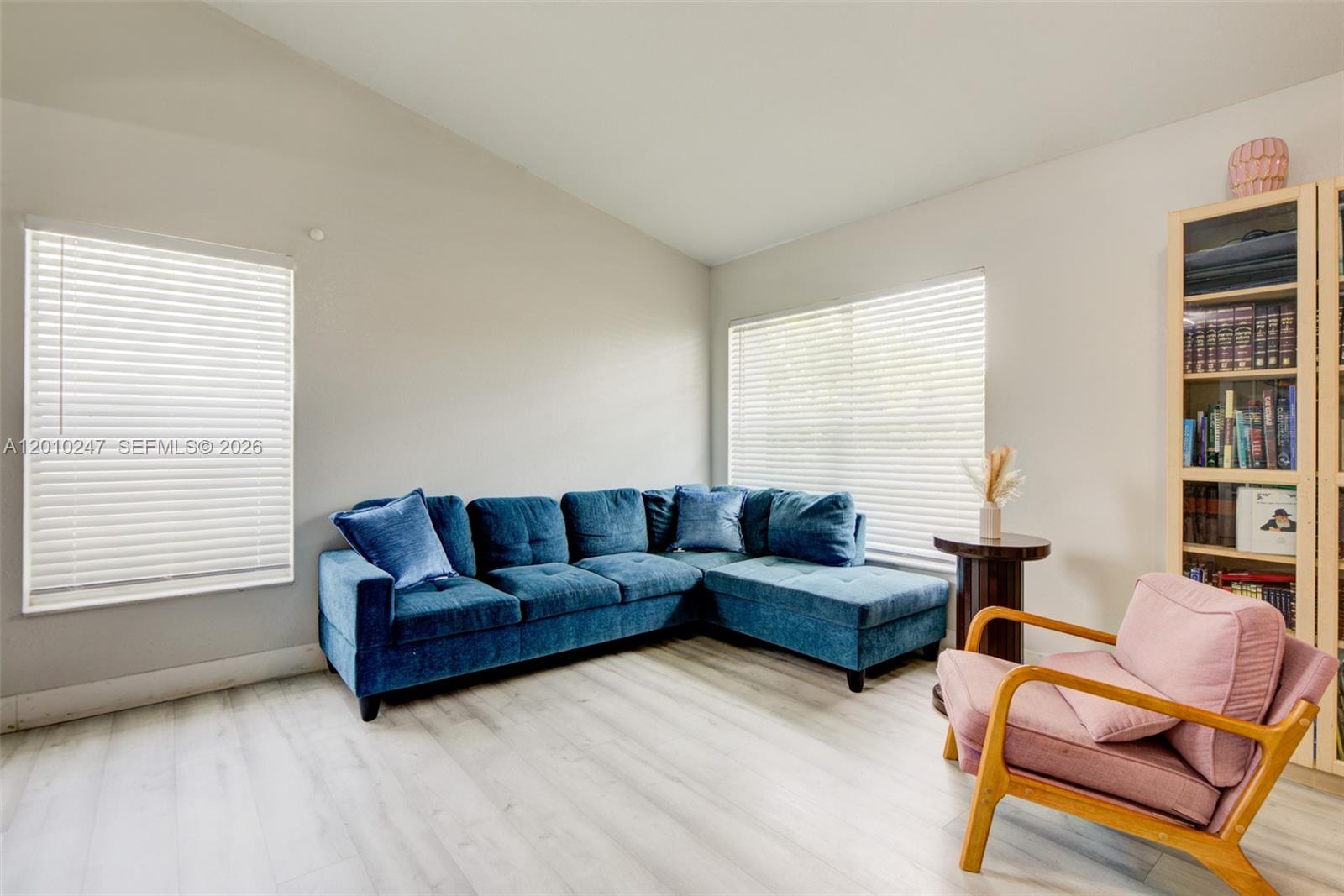 A living room features a blue sectional sofa, a pink armchair, and a wooden bookshelf — 7454 NW 48th Pl, Lauderhill FL 33319, LAUDERHILL, FL