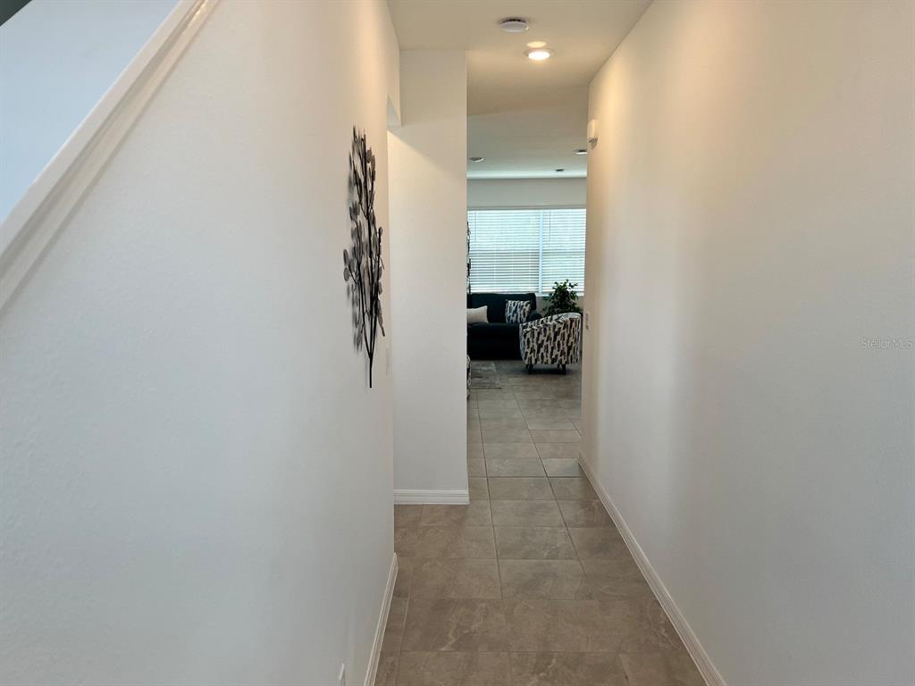 A hallway with tile flooring leads to a living area with a window and furniture — 955 CONCH ROAD, DAVENPORT, FL