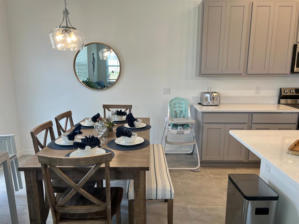A dining area with a wooden table, chairs, bench, and a high chair near cabinets — 955 CONCH ROAD, DAVENPORT, FL