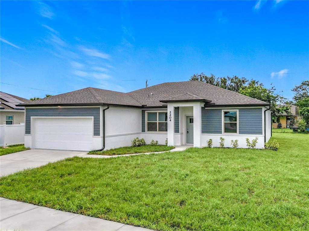 A single-story house features a white stucco and blue siding exterior with a two-car garage — 1211 S SAN MATEO DRIVE, NORTH PORT, FL