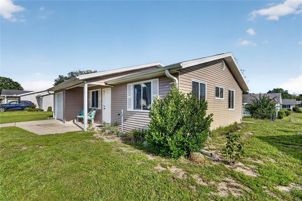A single-story house with tan horizontal siding, a small front porch, and a grassy yard — 8392 SW 108TH LANE, OCALA, FL