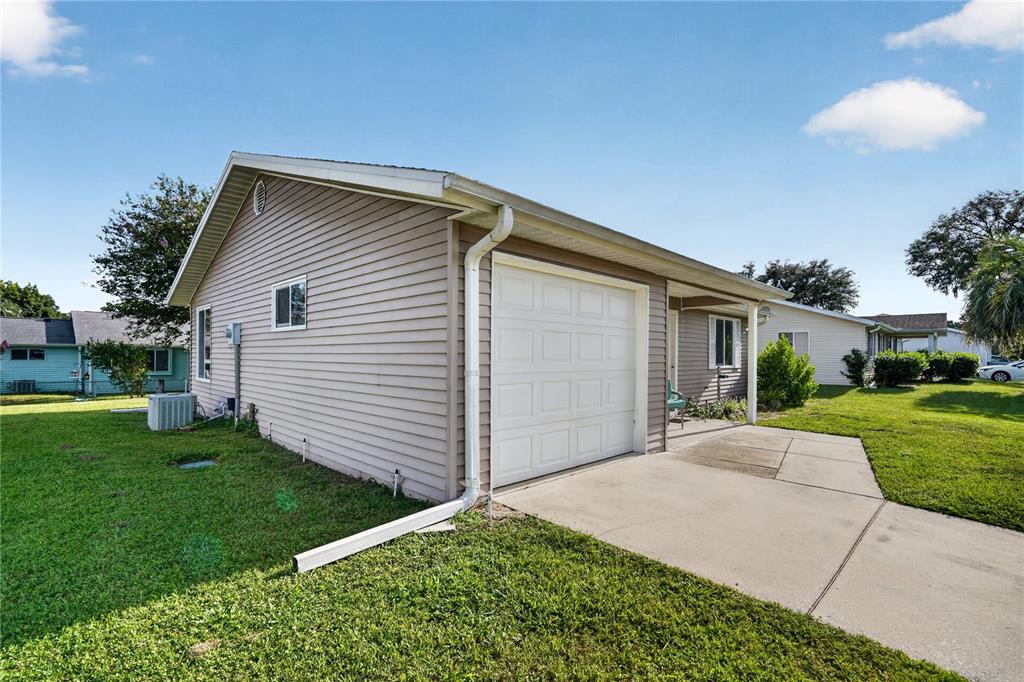 A beige, single-story house with a white garage door and a concrete driveway — 8392 SW 108TH LANE, OCALA, FL