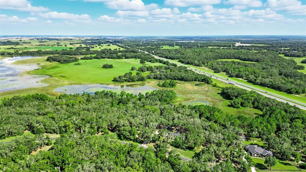 An aerial view shows a house nestled in a wooded area near a highway and wetlands — 3155 BRIGHT LAKE CIRCLE, GROVELAND, FL